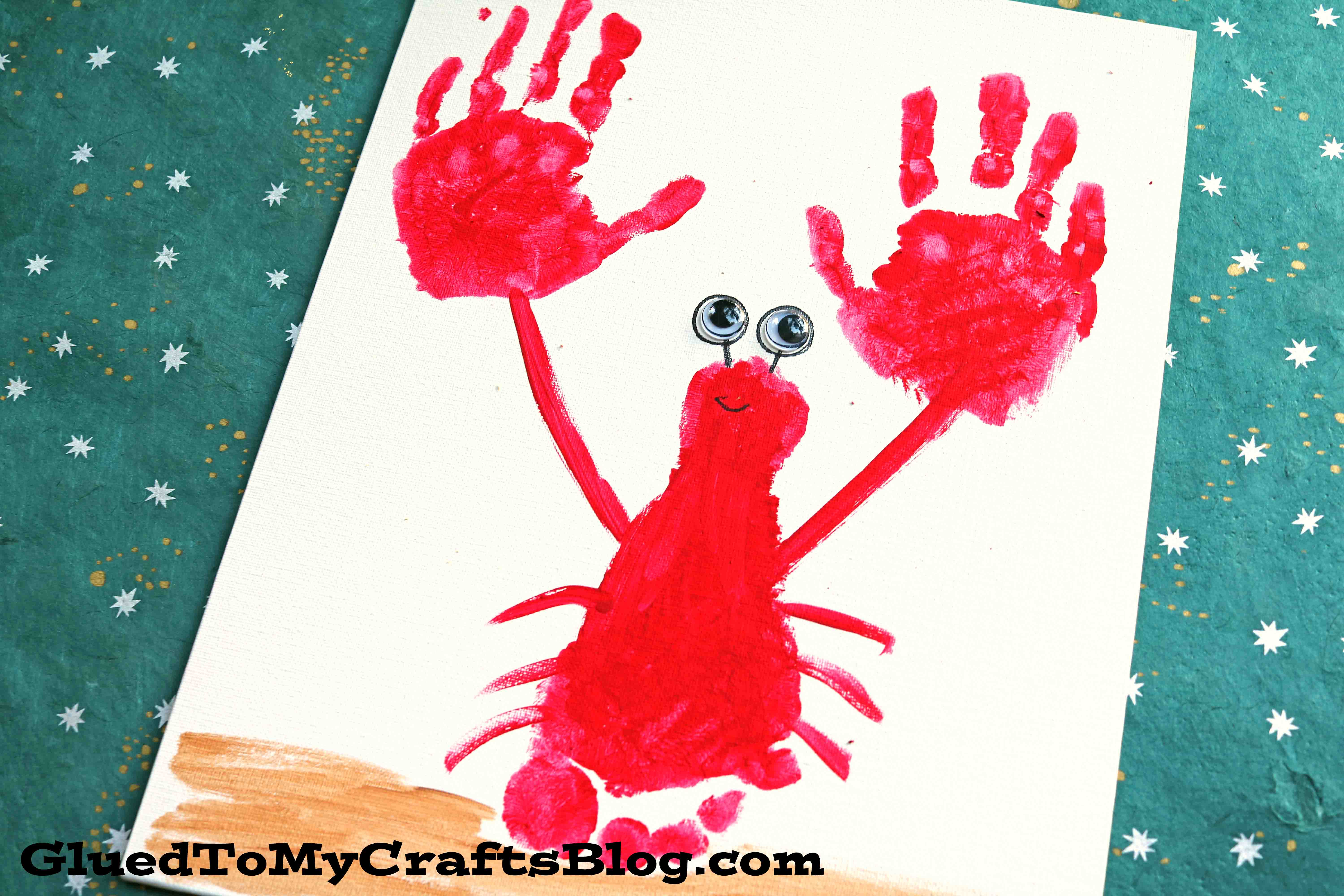 A painted craft of a red crab, resembling a handprint lobster, made from a handprint and two red hand shapes for claws, with googly eyes and a small smile on white paper. The teal background features white and yellow stars.