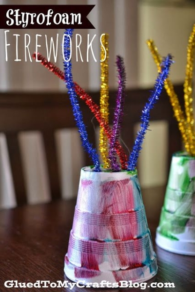 Painted Styrofoam cups with colorful, sparkly pipe cleaners sticking out, resembling fireworksāthis delightful Styrofoam Cup Fireworks project is perfect as a fireworks kid craft! Text reads āStyrofoam Fireworksā and āGluedToMyCraftsBlog.com.ā.