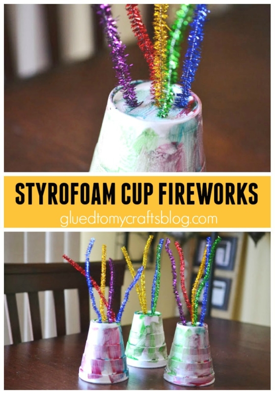 Three decorated Styrofoam cups stand upside down with colorful glitter pipe cleaners poking out from the tops, creating a fireworks effect. This easy fireworks kid craft is featured as āSTYROFOAM CUP FIREWORKSā on gluedtomycraftsblog.com.