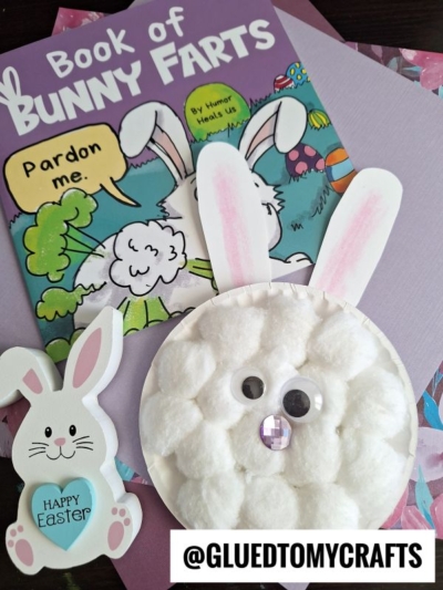 A children’s book titled Book of Bunny Farts with a cartoon bunny on the cover sits behind a bunny cotton ball craft and a Happy Easter bunny cutout. The username @GLUEDTOMYCRAFTS appears at the bottom.