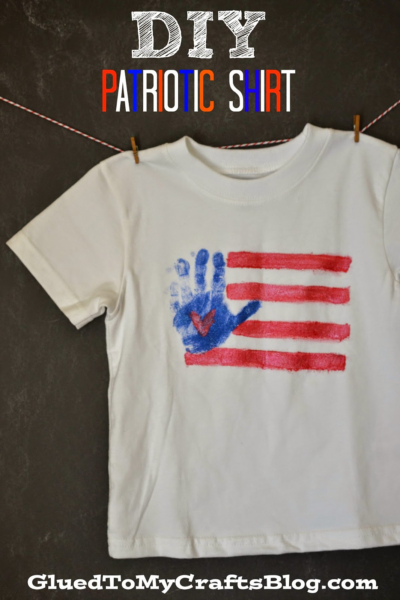 A white t-shirt hangs on a line, decorated with red stripes and a blue handprint flag, resembling an American flag. The text above reads DIY Patriotic Shirt. The bottom has the website GluedToMyCraftsBlog.com.