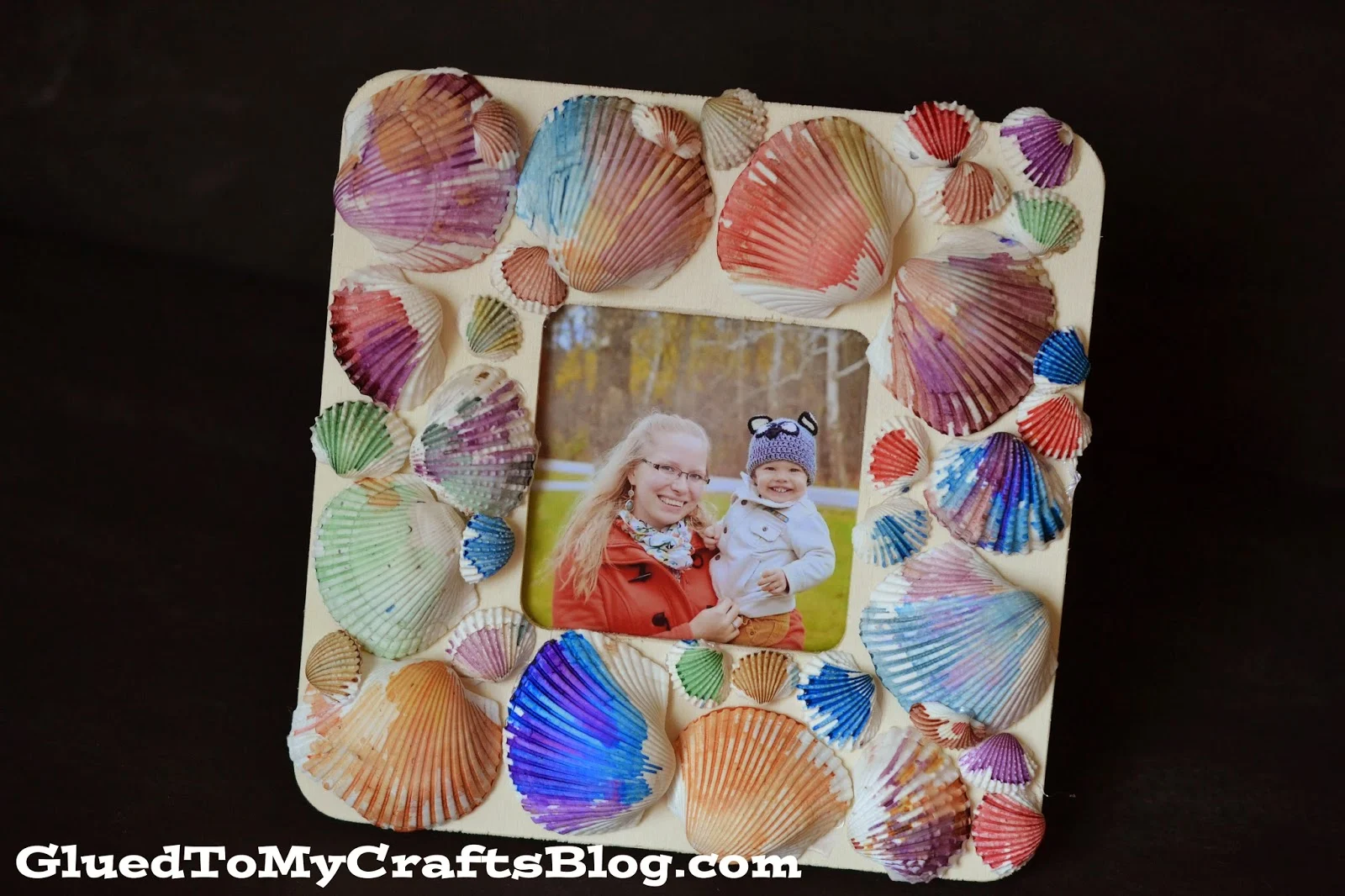 A square Watercolor Seashell Frame decorated with vibrant, hand-painted seashells displays a photo of a woman and a baby.