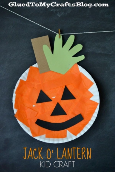 A paper plate jack-o-lantern craft—perfect as a Paper Plate Pumpkin! Made with orange tissue, a black paper face, a brown stem, and a green handprint leaf, this adorable project hangs by a string. Great for showing kids how to make a pumpkin with paper plate materials. Text reads JACK O LANTERN KID CRAFT.