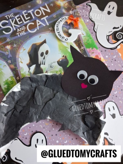 A Halloween-themed craft scene featuring The Skeleton and the Cat book, a delightful Paper Plate Black Cat craft with googly eyes, and ghost-themed paper. The handle @GLUEDTOMYCRAFTS appears in several places.
