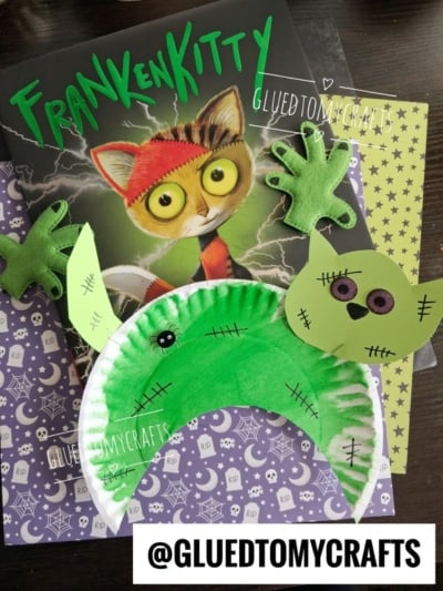 Childrens FrankenKitty book with handmade green Frankenstein-inspired crafts, including a crescent-shaped Paper Plate Black Cat, green felt paws, and a green cat face, on a patterned background. Text: @GLUEDTOMYCRAFTS.