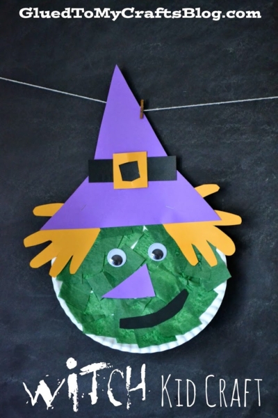 A paper plate halloween witch craft with a green face, orange paper hair, googly eyes, a purple hat, and a paper nose hangs against a dark background. “Witch Kid Craft” is written at the bottom.