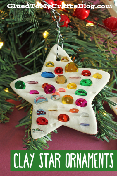 A white clay sequined Christmas ornament shaped like a star hangs on a tree branch adorned with red berries and string lights. The image text reads CLAY STAR ORNAMENTS. Perfect as an air dry ornament for your festive decor!.