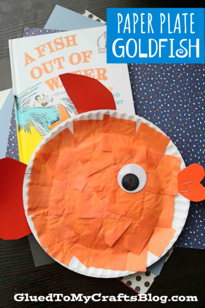 A paper plate goldfish decorated with orange tissue, red fins, and a big googly eye sits atop a book titled A Fish Out of Water, inspired by the Dr. Seuss fish. Text reads Paper Plate Goldfish.