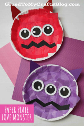 Two paper plate monsters, one red and one purple, decorated with tissue paper, big cartoon eyes, zigzag mouths, and triangle ears, are shown on pink and purple backgrounds. Text reads Paper Plate Love Monster—a fun love monster craft for kids.