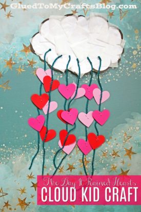 A handmade Rained Hearts Craft featuring a tissue paper cloud with green yarn strands, each holding red and pink hearts, set against a blue starry background. Text reads: The Day It Rained Hearts CLOUD KID CRAFT.