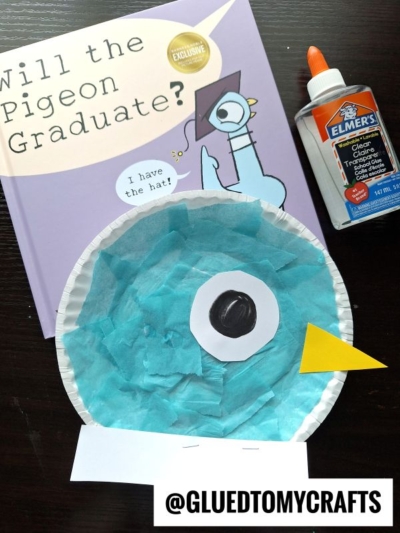 A children’s book titled Will the Pigeon Graduate?, a bottle of Elmer’s glue, and a Paper Plate Pigeon craft made with blue tissue paper, paper shapes, and the handle @GLUEDTOMYCRAFTS are shown.