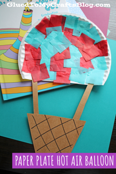 A Plate Hot Air Balloon craft inspired by "Seuss Oh The Places You'll Go," made with a paper plate, red and blue tissue squares, and a brown paper basket, rests on a colorful book. Text reads, PAPER PLATE HOT AIR BALLOON.