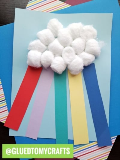 A St. Patty's Day craft features a fluffy cotton ball cloud with colorful paper strips (red, pink, yellow, green, and blue) hanging like rain. @GLUEDTOMYCRAFTS appears in a green box at the bottom left.