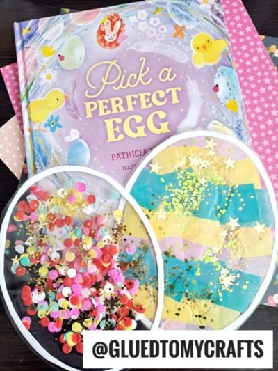 Two colorful Easter egg crafts, including a sparkling stained glass easter egg suncatcher and one with strips of paper and glitter, are displayed beside the book Pick a Perfect Egg. Pink polka dot paper creates a cheerful backdrop.