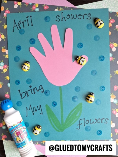A blue card features an Easter Kid Craft—a pink handprint flower with “April showers bring May flowers” around it, blue dots as raindrops, decorative bee buttons, and a green stem. @GLUEDTOMYCRAFTS tag at the bottom.