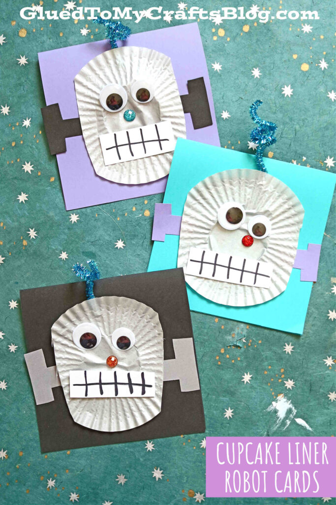 Three handmade Cupcake Liner Robots cards made from white cupcake liners with googly eyes, paper features, and blue pipe cleaner antennas are displayed on colorful square backgrounds. Text reads CUPCAKE LINER ROBOT CARDS.