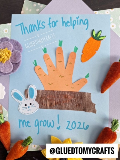 A handmade Easter Kid Craft features a cut-out handprint as a carrot growing from brown paper soil, decorated with a felt bunny, carrots, and flowers. Text reads “Thanks for helping me grow! 2026.” The handle @GLUEDTOMYCRAFTS is at the bottom.