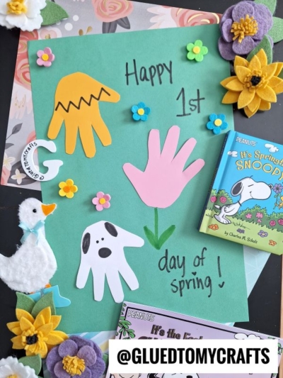 A colorful Easter Kid Craft features paper cutouts of a hand, chick, and ghost on a green background, surrounded by felt flowers, a felt duck, and Peanuts books. Text reads Happy 1st day of spring!.