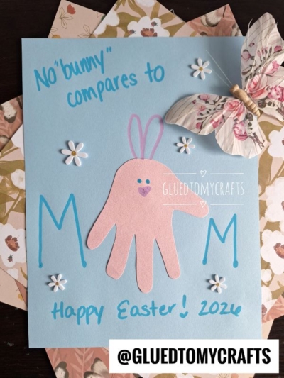 A handmade Easter Kid Craft card features a pink handprint bunny, blue text reading “No ‘bunny’ compares to M♥M,” white daisies, a butterfly decoration, and “Happy Easter! 2026.” Username @GLUEDTOMYCRAFTS at the bottom.