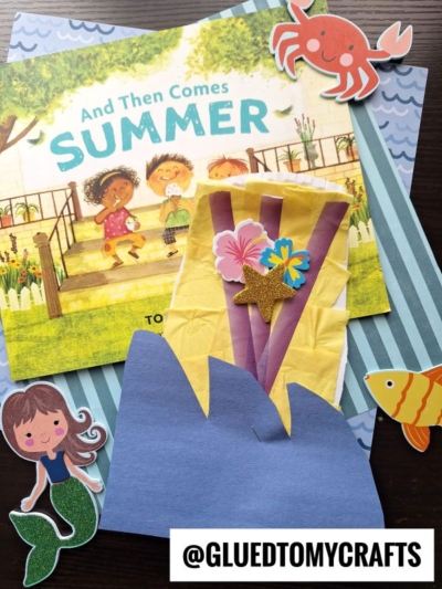 A colorful summer-themed craft scene with the book And Then Comes Summer, paper cutouts of a crab, fish, and mermaid, a handmade sun, flowers, blue waves, and a fun paper plate surfboard. The handle @GLUEDTOMYCRAFTS is at the bottom.