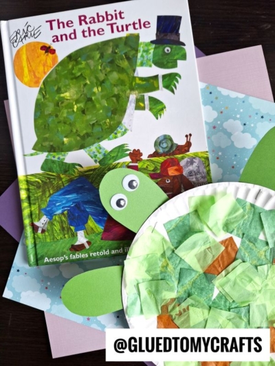 A children’s book titled The Rabbit and the Turtle is displayed with a green turtle craft made from a paper plate, green paper, and tissue paper—an adorable Eric Carle craft that resembles the turtle on the book cover.