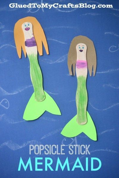 Two craft stick mermaids with paper hair and tails, colored faces, and green fins are displayed on a blue background with “Popsicle Stick Mermaid” written below.