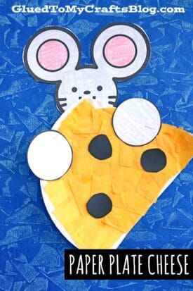 A cute paper plate cheese craft features a mouse with pink ears and a sweet face, peeking over a yellow cheese wedge with black spots, all set on a textured blue background. Text reads, Paper Plate Cheese.