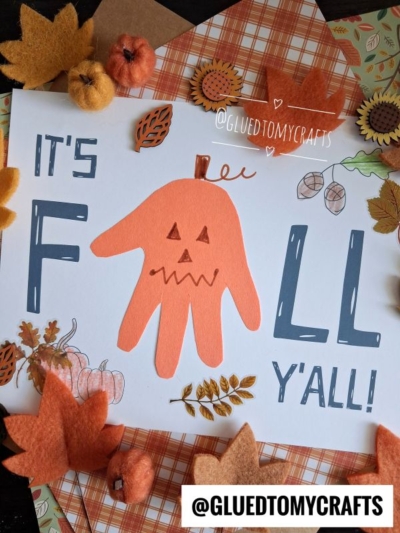 A craft sign reads Its FALL Yall! with the word FALL featuring an orange handprint jack-o-lantern as the A, surrounded by autumn leaves, pumpkins, a colorful paper plate leaf, and the Instagram handle @GLUEDTOMYCRAFTS.
