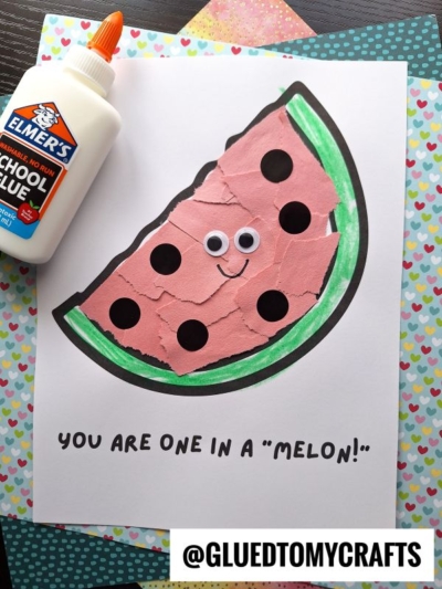 A handmade watermelon craft with torn paper, googly eyes, and a smile sits on white paper. Perfect for Fruit & Veggie crafts, it features the text YOU ARE ONE IN A MELON! Glue and patterned papers are nearby for extra fun.