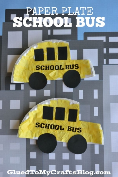 Two yellow paper plate bus crafts with black wheels and windows are displayed on a gray cityscape background. Text reads PAPER PLATE SCHOOL BUS and GluedToMyCraftsBlog.com, highlighting this creative school bus craft idea.