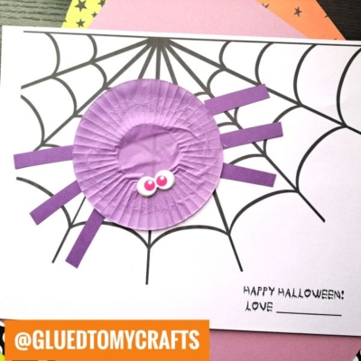 A Halloween craft shows a purple cupcake liner spider made from a cupcake liner and paper strips on a spider web drawing, with space to write Happy Halloween! and Love: ___.