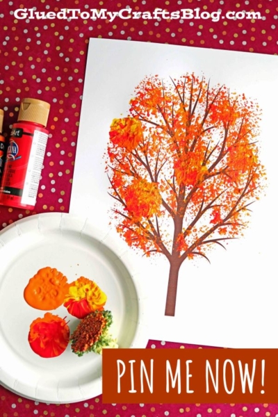 A broccoli stamped fall tree craft made with a printed tree outline and painted leaves in orange, yellow, and red. Paint bottles, a plate with paint, and a sponge are nearby on a red polka dot surface. Text reads PIN ME NOW!.