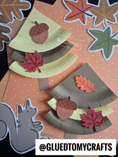 Two paper crafts shaped like autumn trees with acorn and leaf decorations, placed on an orange polka dot background with fall-themed cutouts and a squirrel illustration—perfect inspiration for your next Fall Craft Ideas project. A @GLUEDTOMYCRAFTS label is at the bottom.