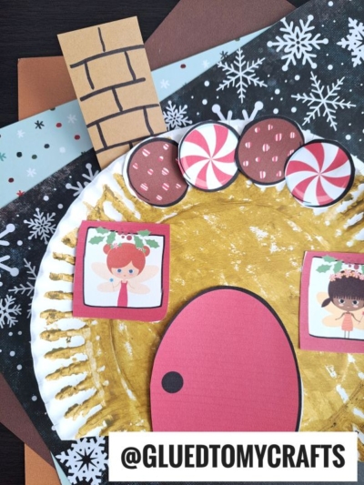 A festive Paper Plate Gingerbread House craft features a gold-painted plate with a pink door, candy decor, angel drawings in the windows, and a paper chimney, set on brown, black, and snowflake-patterned paper. @GLUEDTOMYCRAFTS appears at the bottom.