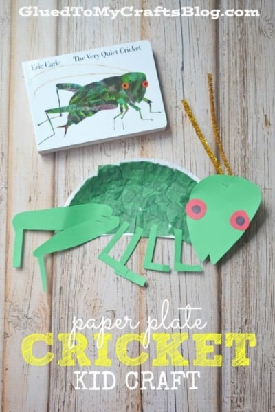 A handmade Paper Plate Cricket with green paper plates and pipe cleaner antennae lies next to the book The Very Quiet Cricket. The text reads, paper plate cricket kid craft.