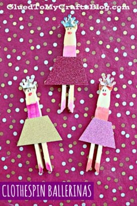 Three clothespin ballerinas with colorful skirts, crowns, and drawn faces are arranged on a pink polka-dotted background. The text Clothespin Ballerinas appears at the bottom, celebrating charming wood ballerina crafts.