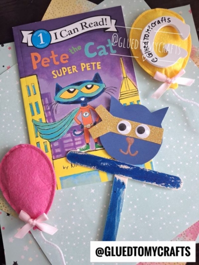 A Pete the Cat: Super Pete book is displayed alongside a handmade Pete The Cat puppet mask on a stick and two felt balloons, all arranged on pastel paper. The @GLUEDTOMYCRAFTS handle appears twice in the image.