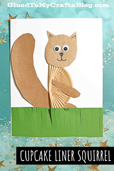 A cupcake liner squirrel made from brown cupcake liners and construction paper sits on white paper, featuring googly eyes, a big tail, drawn nose and mouth, plus green paper grass. Text reads CUPCAKE LINER SQUIRREL.