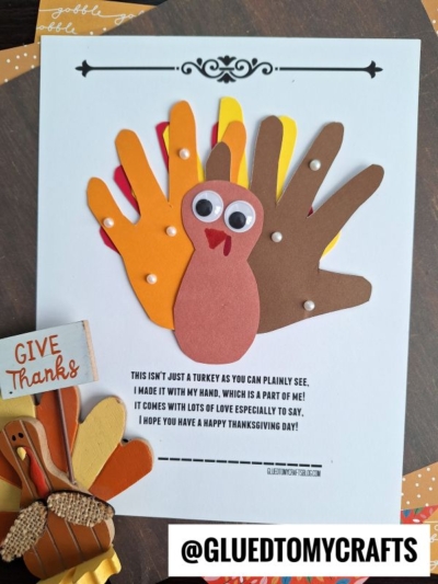 A Thanksgiving craft with layered paper handprints forming a charming handprint turkey, googly eyes, and a sweet handprint turkey poem about handmade gifts. @GLUEDTOMYCRAFTS is visible at the bottom. Other turkey crafts and a Give Thanks sign are nearby.