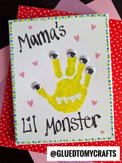 A handmade card reads "Mamas Lil Monster" with hearts, featuring a yellow painted handprint with googly eyes on each fingertip—perfect for a Mommy's Little Monster Handprint Idea—and bordered with colorful dots.