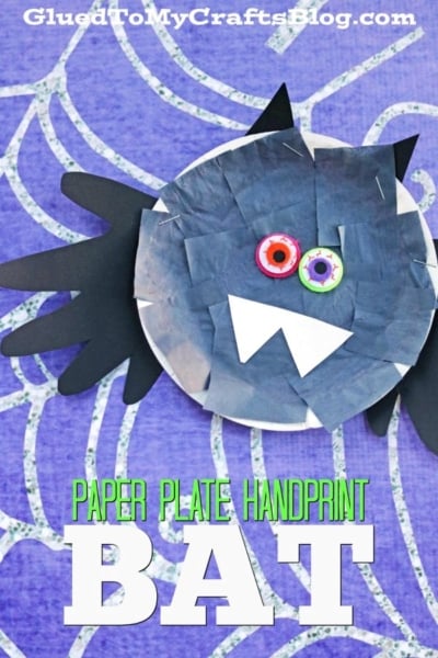 A paper plate handprint bat craft features handprint wings, big googly eyes, and white paper fangs, all displayed on a purple patterned background. Text reads, Paper Plate Handprint Bat.