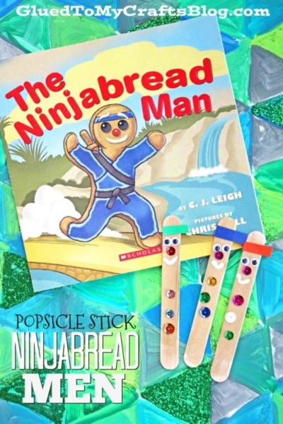 Children’s book “The Ninjabread Man” is displayed with three popsicle stick ninjabread men, each decorated with colorful gems and paper belts, on a vibrant, textured background.