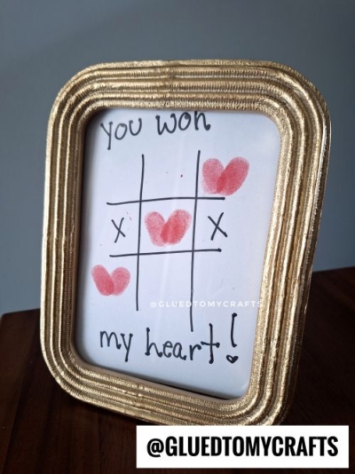 A framed tic-tac-toe game features Xs and red heart shapes as Os. Above, it reads You won, and below, my heart! Perfect as a valentine card kid craft, the frame sits on wood with @GLUEDTOMYCRAFTS at the bottom.
