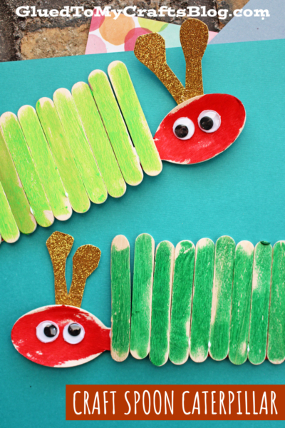 Two caterpillars made from green-painted popsicle sticks and red spoon heads with googly eyes and gold glitter antennae, displayed on a blue background. Text reads CRAFT SPOON CATERPILLAR—a fun popsicle stick caterpillar craft.