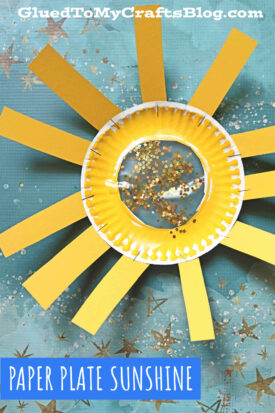 A craft project featuring a yellow paper plate sun suncatcher with glitter in the center and yellow paper strips glued around it to resemble sunshine, displayed on a blue star-patterned background. Text reads Paper Plate Sunshine.