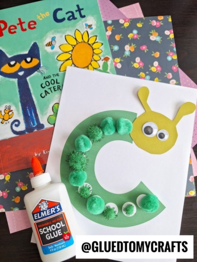 A craft project features a green letter C decorated as a pom pom caterpillar with googly eyes, next to a bottle of Elmer’s glue and the book Pete the Cat and the Cool Caterpillar.