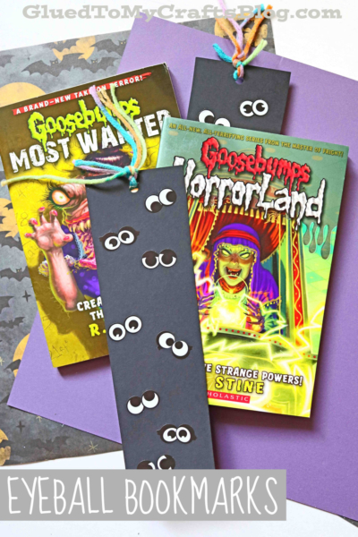 Two Goosebumps books lay on purple paper with handmade black Eyeball Halloween Bookmarks, decorated with googly eyes and colorful yarn tassels. Text at the bottom reads Eyeball Bookmarks.