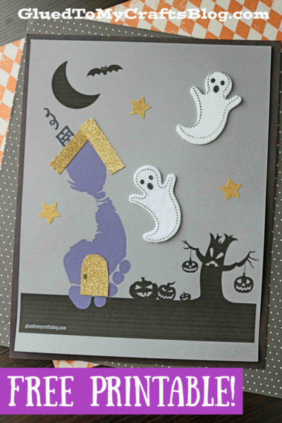 A Halloween craft featuring a footprint haunted house with a gold glitter roof, two friendly ghost cutouts, stars, a bat, crescent moon, pumpkins, and spooky tree on a gray background. Text reads FREE PRINTABLE!.