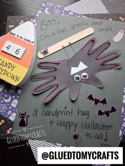 Children’s Halloween craft with a bat made from a handprint, googly eyes, and a craft stick—perfect for creating halloween keepsakes. The page says Boo! I’m a bat, spooky and small, a handprint hug + Happy Halloween to all! with Halloween stickers.