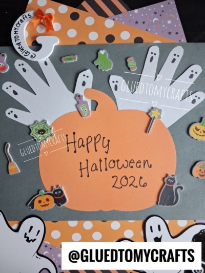 A Halloween craft features a paper pumpkin, white handprint cutouts as ghosts, stickers of cats, bats, and pumpkins—perfect for creating cherished halloween keepsakes. The text “Happy Halloween 2026” with the handle @GLUETOMYCRAFTS adds a festive touch.